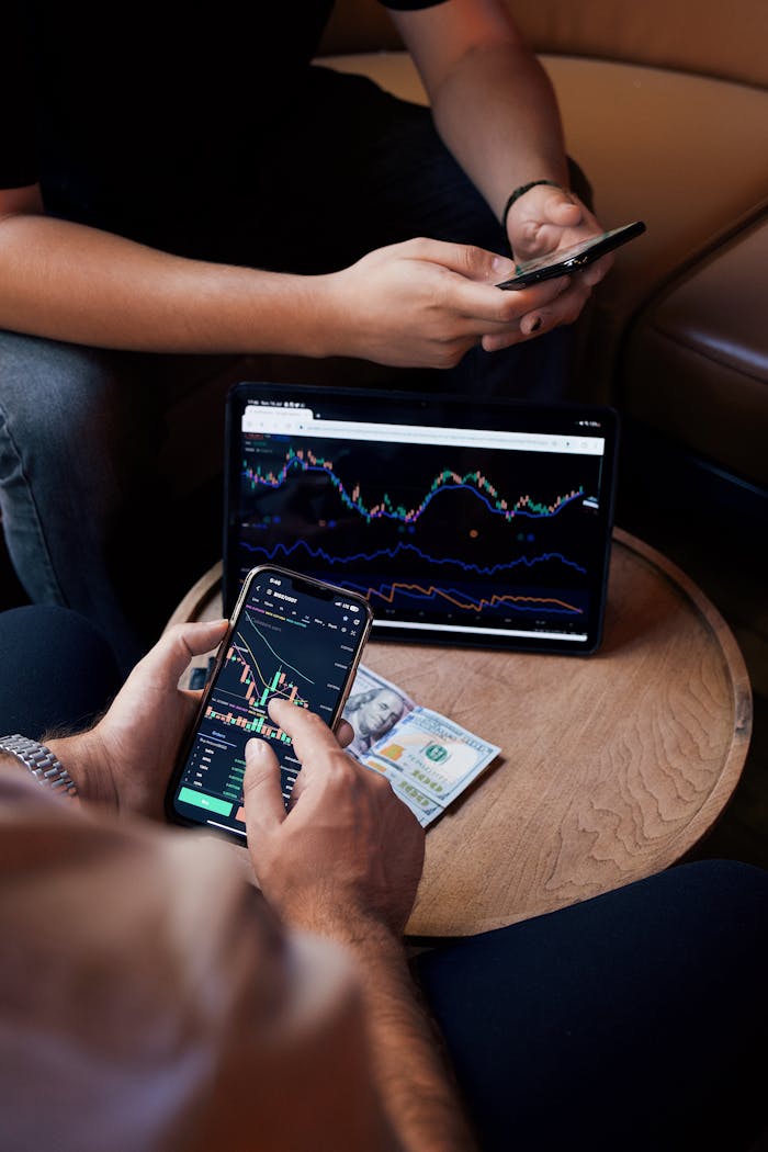 portfolio-02 Two people using smartphone and tablet for trading stocks indoors.