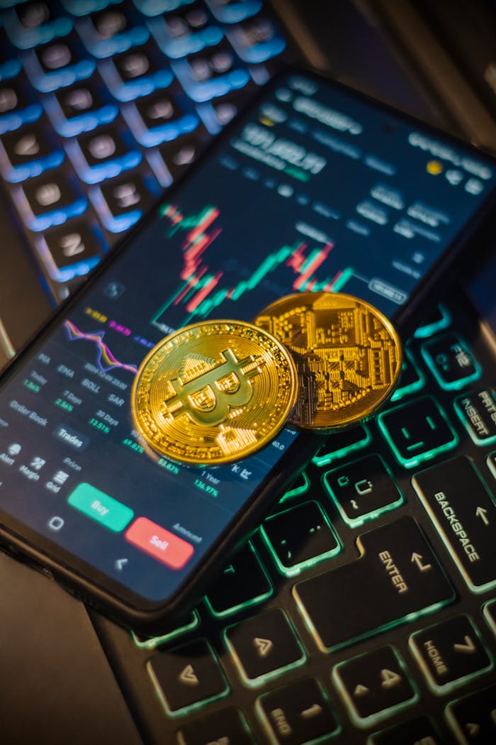 gallery-04 Cryptocurrency trading interface on a mobile with Bitcoin coins on a laptop keyboard.