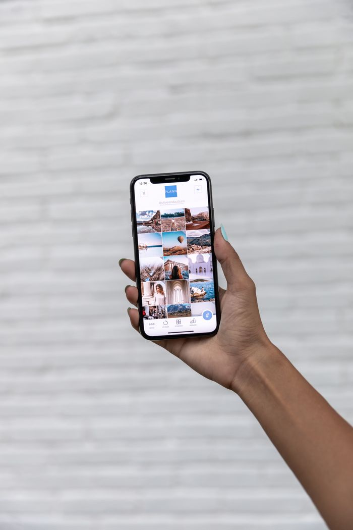 services-08 A hand holding a smartphone displaying travel photos against a white textured background.