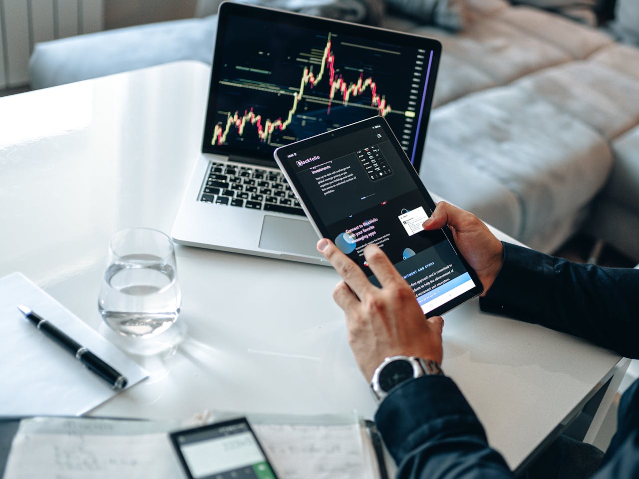 portfolio-02 Person analyzing digital market trends on tablet with laptop showing financial charts.